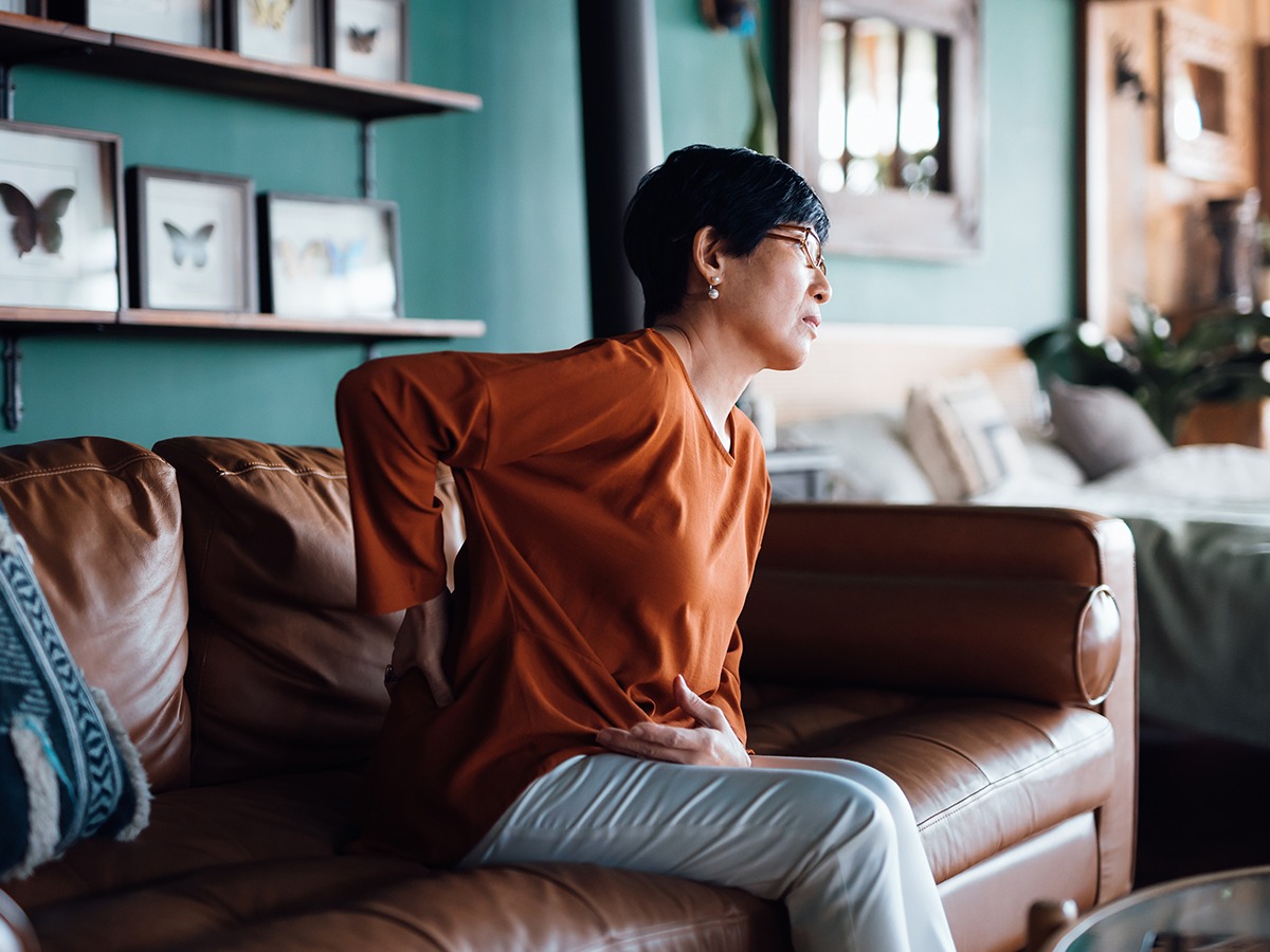 Person sitting on couch with hand on their back