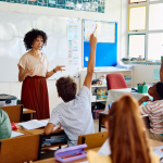 Teacher stands at the front of a classroom full of children.