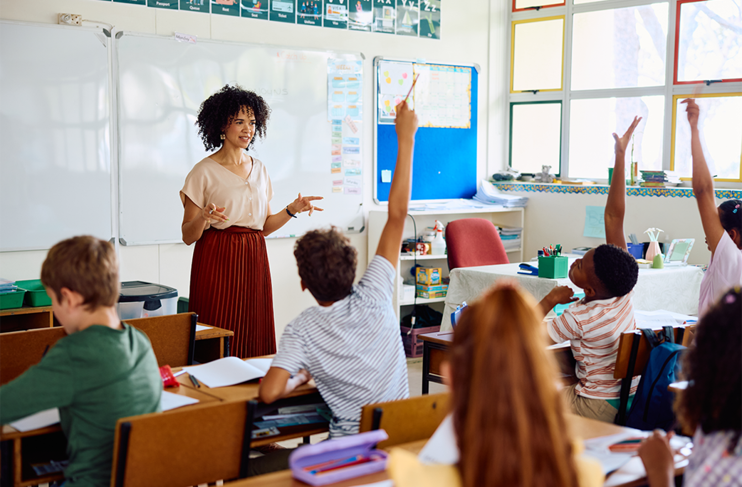 Teacher stands at the front of a classroom full of children.