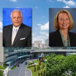 Composite image showing two professional headshots positioned above the entrance of a large modern hospital building. The headshot on the left features a man in a dark suit and light tie against a blue background. The headshot on the right features a woman in a dark blazer and patterned scarf against a gray-blue background. The hospital campus is visible below, with glass-fronted architecture, a circular drive, trees, and a partly cloudy sky.
