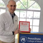 Dr. Michael McShane holds a framed award while standing at a podium.