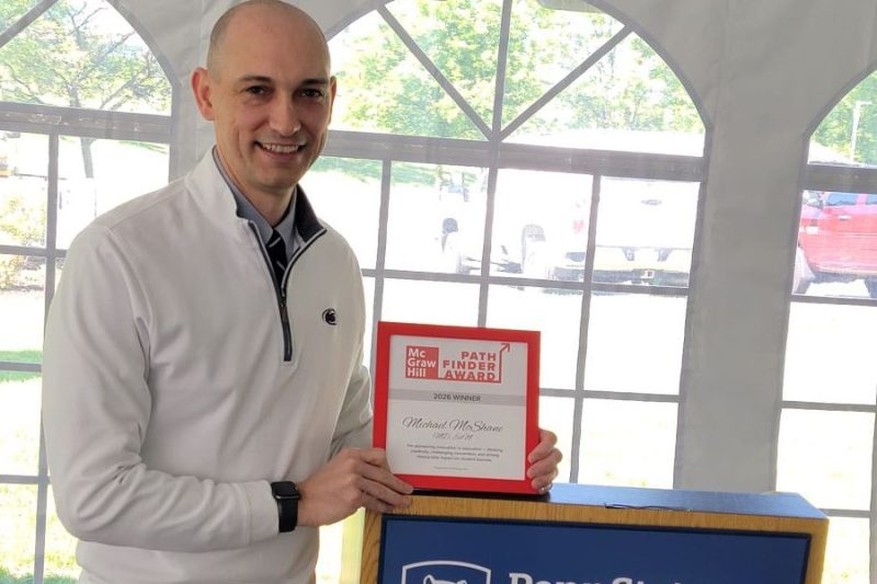 Dr. Michael McShane holds a framed award while standing at a podium.