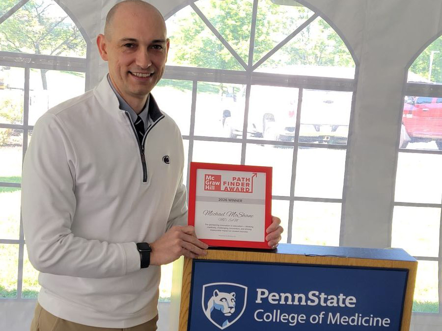 Dr. Michael McShane holds a framed award while standing at a podium.