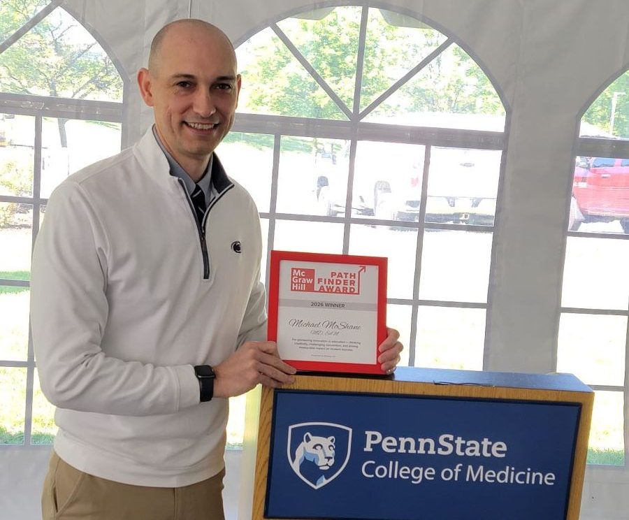 Dr. Michael McShane holds a framed award while standing at a podium.
