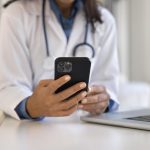 A close-up of a doctor holding a smartphone.