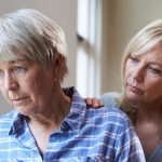 Adult daughter comforts her older mother, who appears sad.