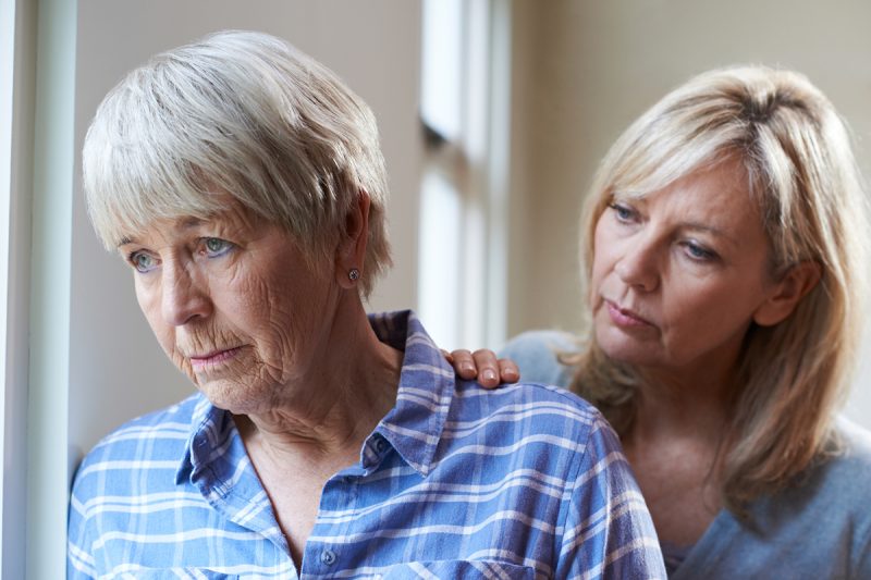 Adult daughter comforts her older mother, who appears sad.