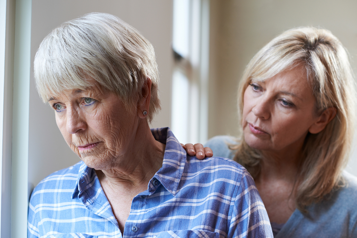 Adult daughter comforts her older mother, who appears sad.