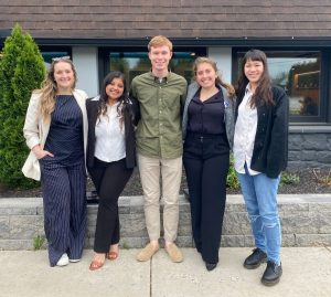 A group of four students stands together in front of a building.