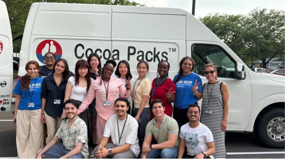 A group of diverse students stands together in front of a Cocoa Packs van.
