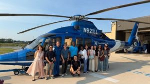 A group of students stands in front of a Life Lion helicopter.