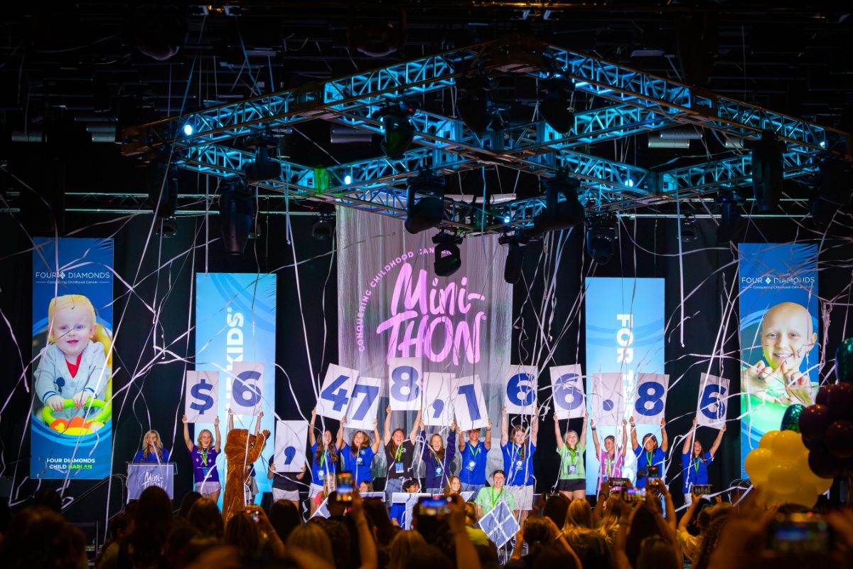 Student leaders on stage at the Four Diamonds Mini-THON Leadership Summit hold oversized number cards revealing the total amount raised for the 2025-26 school year.