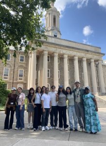 Students stand for a group photo in front of a large building on the University Park campus.
