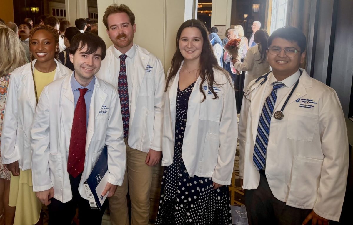 Five students stand together in their new white coats