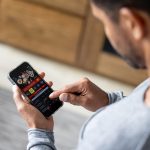 Man gambling online on a football game using his cell phone.