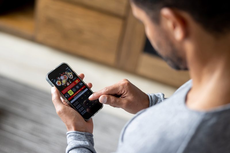 Man gambling online on a football game using his cell phone.