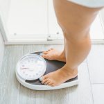 High angle view of a woman standing on a weight scale in a bathroom.