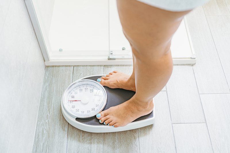 High angle view of a woman standing on a weight scale in a bathroom.