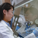 Person in lab coat performs experiment in lab
