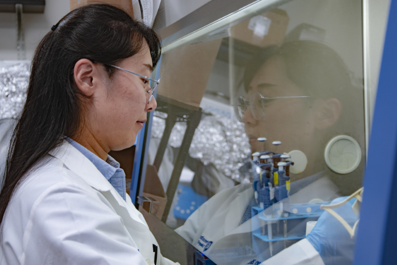 Person in lab coat performs experiment in lab