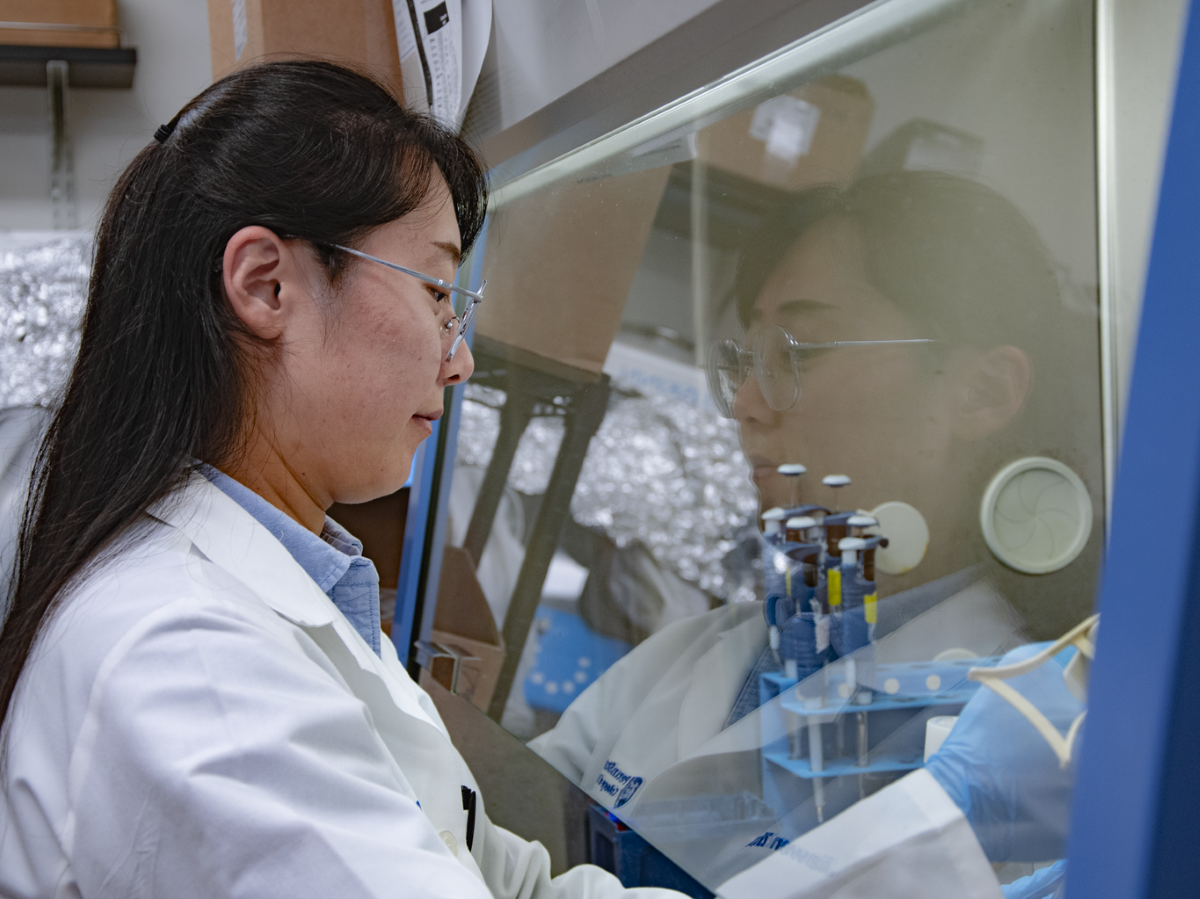 Person in lab coat performs experiment in lab